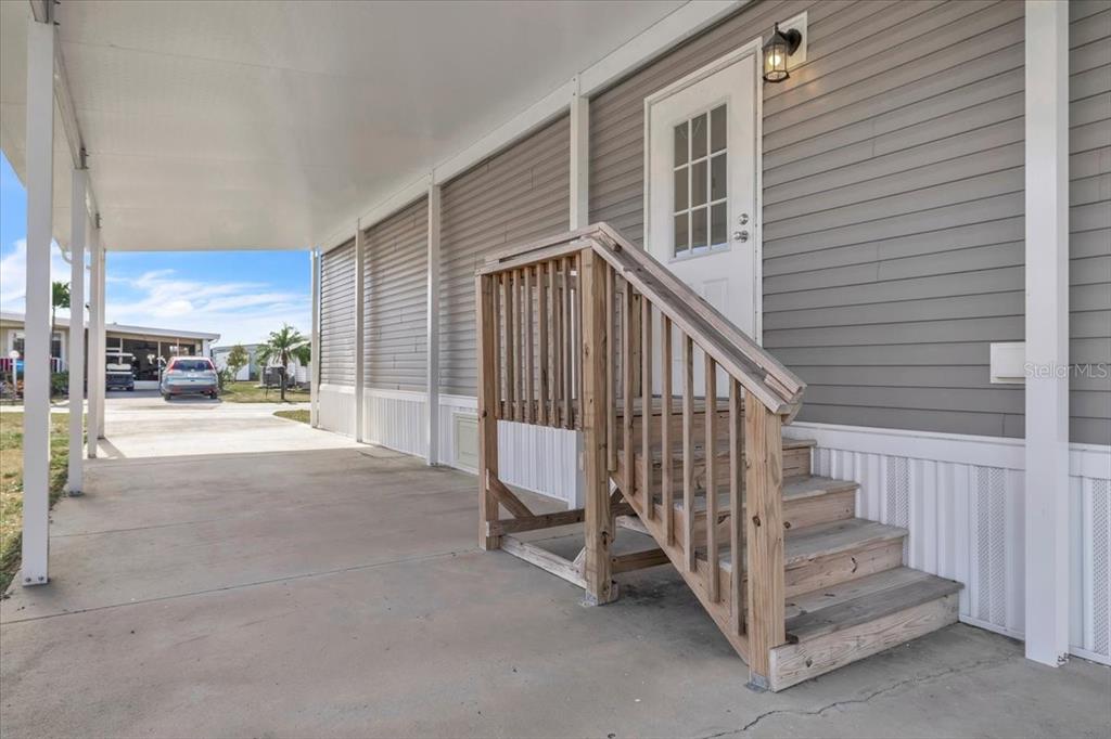 A wooden staircase leads to a white door on the side of a gray house — 3162 MERCURY LANE, NORTH FORT MYERS, FL