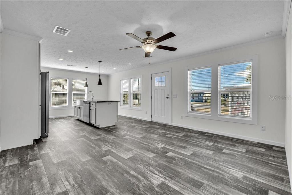 An open-concept kitchen and living area features white cabinetry, a kitchen island, and wood-look flooring — 3162 MERCURY LANE, NORTH FORT MYERS, FL