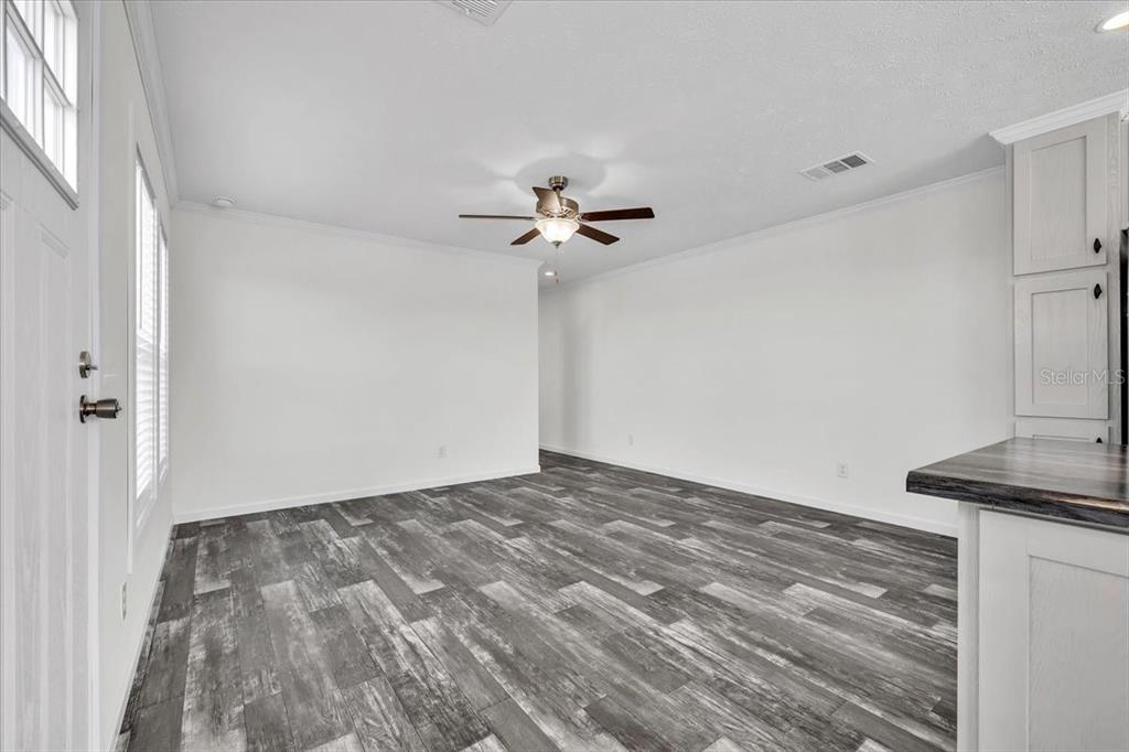 An empty room features white walls, a ceiling fan, and gray wood-look plank flooring — 3162 MERCURY LANE, NORTH FORT MYERS, FL