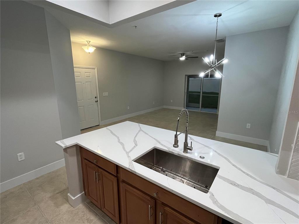 A kitchen features wood cabinets, stainless steel appliances, white countertops, and a tiled backsplash — 3635 PARKRIDGE CIRCLE UNIT 10-101, SARASOTA, FL