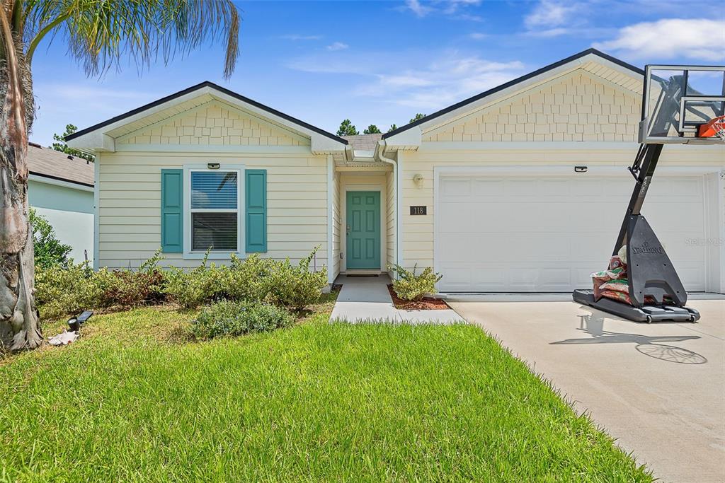 A single-story house with light yellow siding, teal shutters, a front door, and a basketball hoop — 118 HULETT WOODS ROAD, PALM COAST, FL