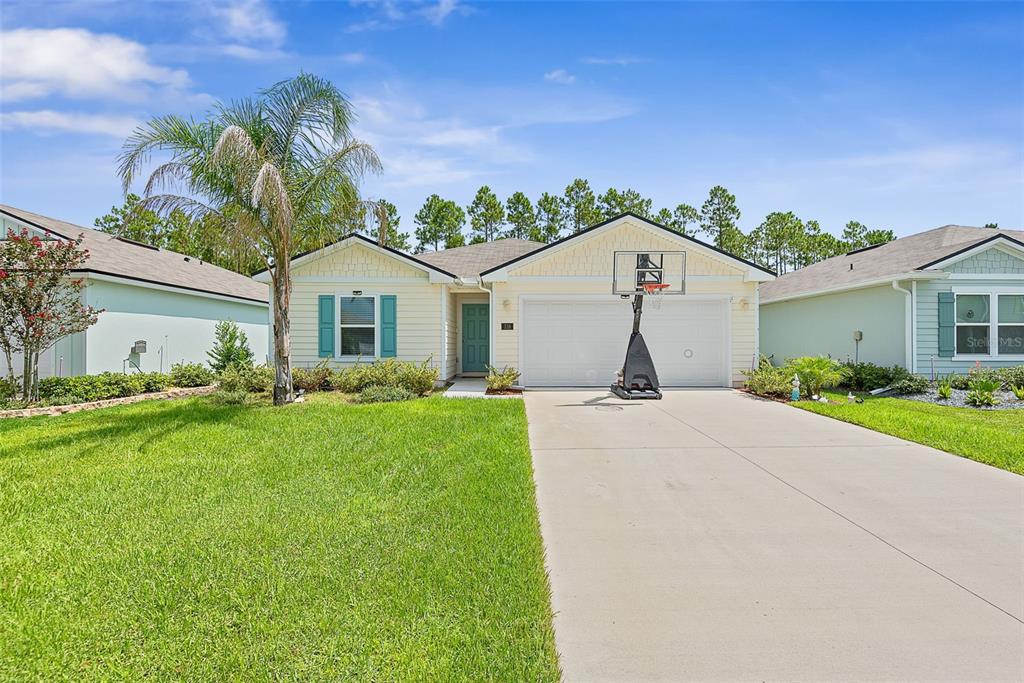 A single-story house with light yellow siding, a two-car garage, and a front lawn — 118 HULETT WOODS ROAD, PALM COAST, FL