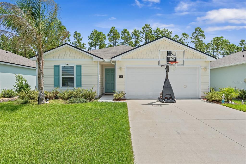 A single-story house with light yellow siding, a two-car garage, and a basketball hoop — 118 HULETT WOODS ROAD, PALM COAST, FL