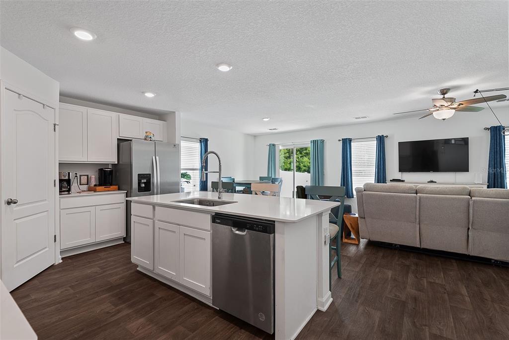 A modern kitchen with white cabinets and a center island opens into a living area — 118 HULETT WOODS ROAD, PALM COAST, FL