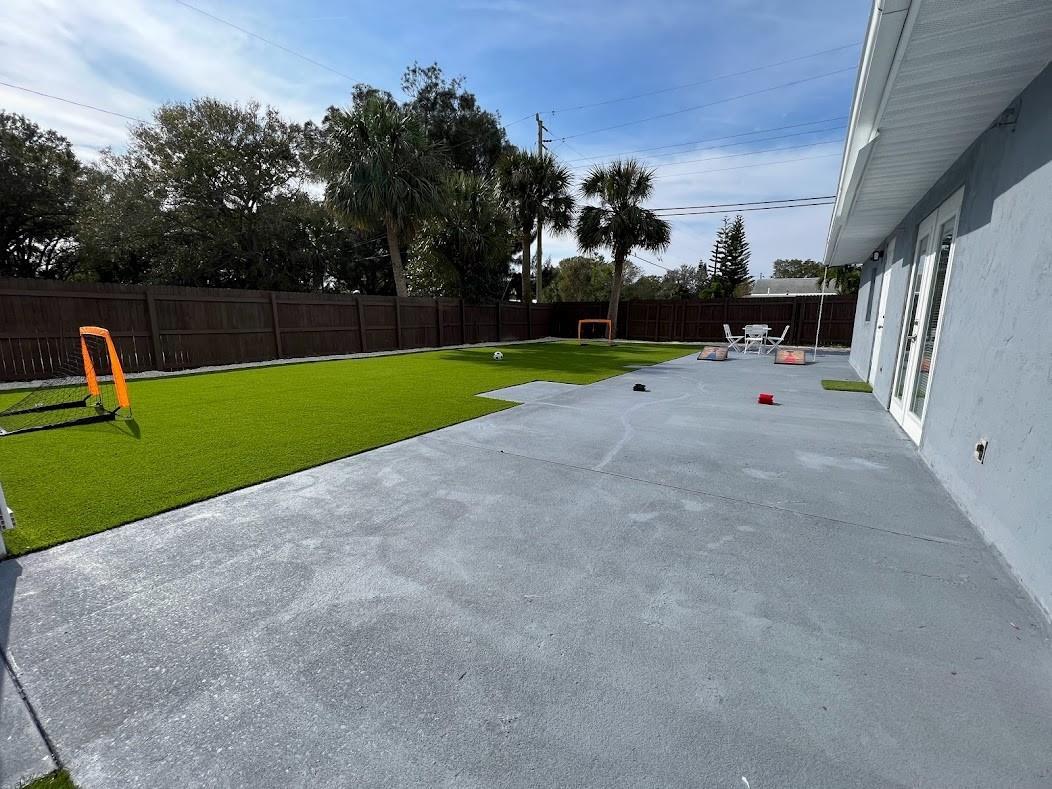 A backyard features a gray concrete patio, artificial turf lawn, and a wooden privacy fence — 1810 Elizabeth Street, Melbourne FL 32901, MELBOURNE, FL