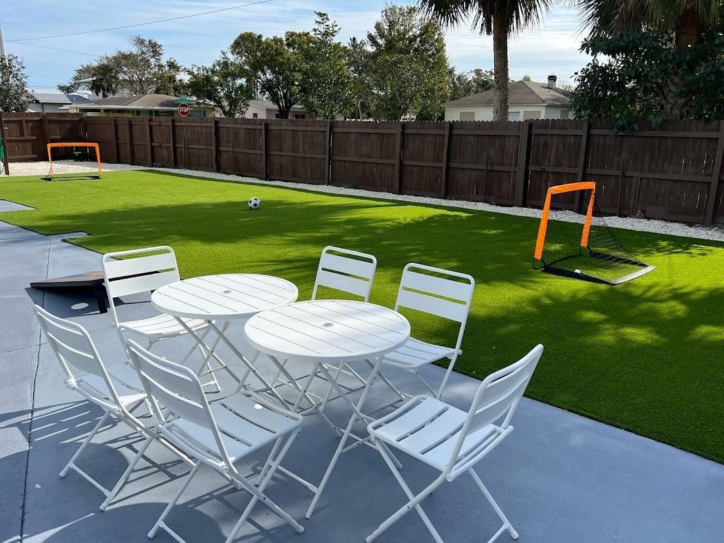 A backyard features a patio with white metal furniture, artificial turf, and two soccer goals — 1810 Elizabeth Street, Melbourne FL 32901, MELBOURNE, FL