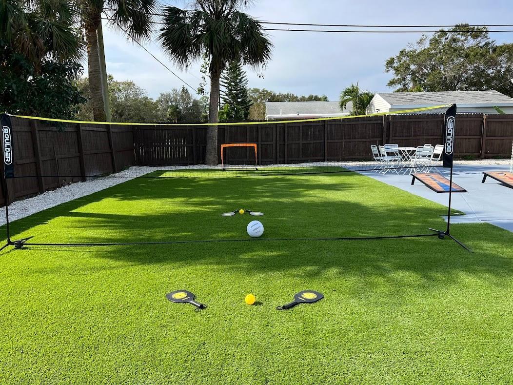 A backyard features a portable net, artificial turf, and various lawn game equipment — 1810 Elizabeth Street, Melbourne FL 32901, MELBOURNE, FL