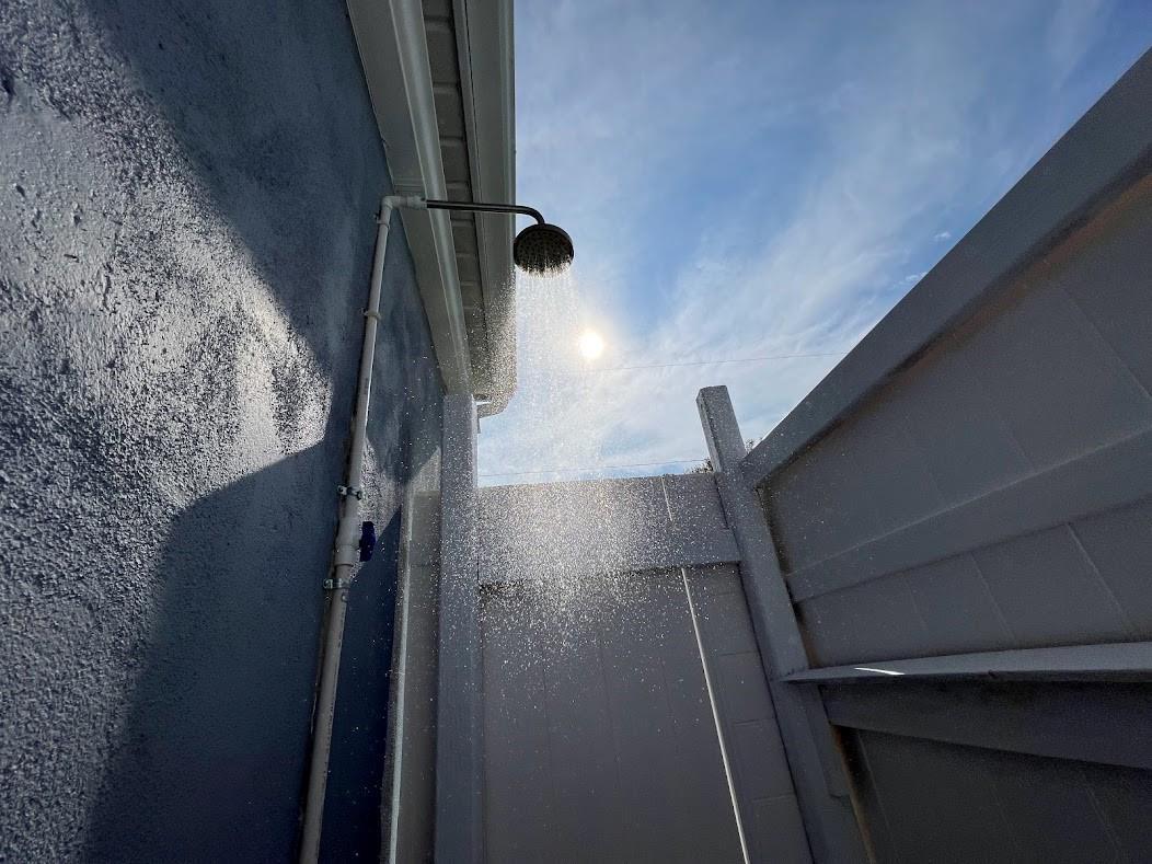 An outdoor shower with a metal showerhead is mounted on a blue exterior wall — 1810 Elizabeth Street, Melbourne FL 32901, MELBOURNE, FL
