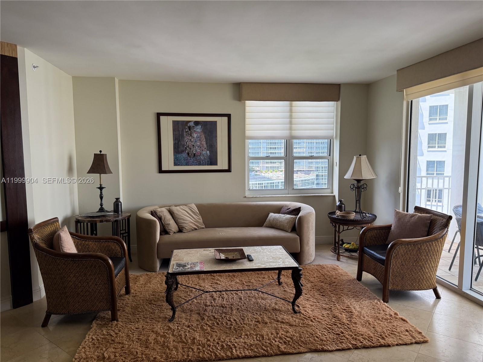 A living room features a curved sofa, two wicker chairs, and a central coffee table — 701 Brickell Key Blvd # 2104, Miami FL 33131, MIAMI, FL