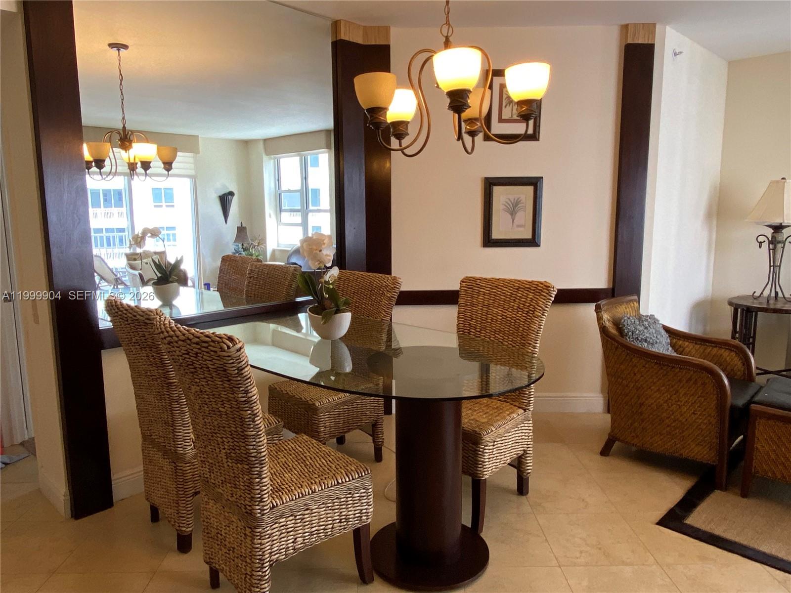 A dining area features a glass-topped table, wicker chairs, a chandelier, and a large mirror — 701 Brickell Key Blvd # 2104, Miami FL 33131, MIAMI, FL