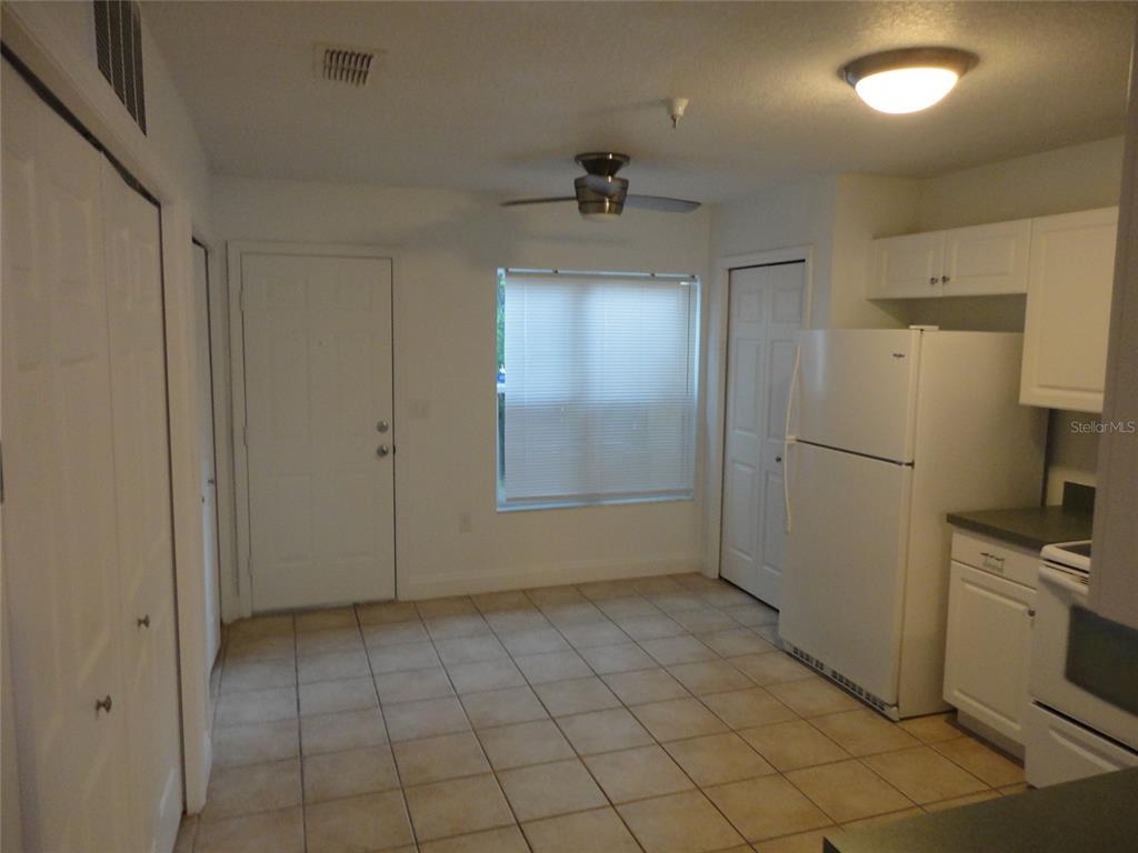 A kitchen and dining area with white cabinets, a white refrigerator, and tiled flooring — 2636 SW 35TH PLACE UNIT 8, GAINESVILLE, FL