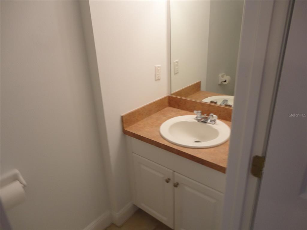 A bathroom features a white vanity with a tan countertop, a sink, and a mirror — 2636 SW 35TH PLACE UNIT 8, GAINESVILLE, FL
