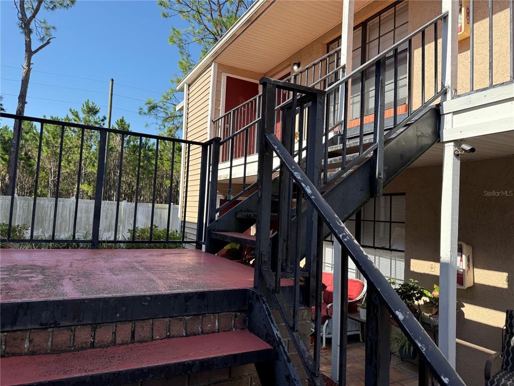 A balcony with a red door, a window with blinds, and a metal railing — 21026 VOYAGER BOULEVARD UNIT 6, LAND O LAKES, FL