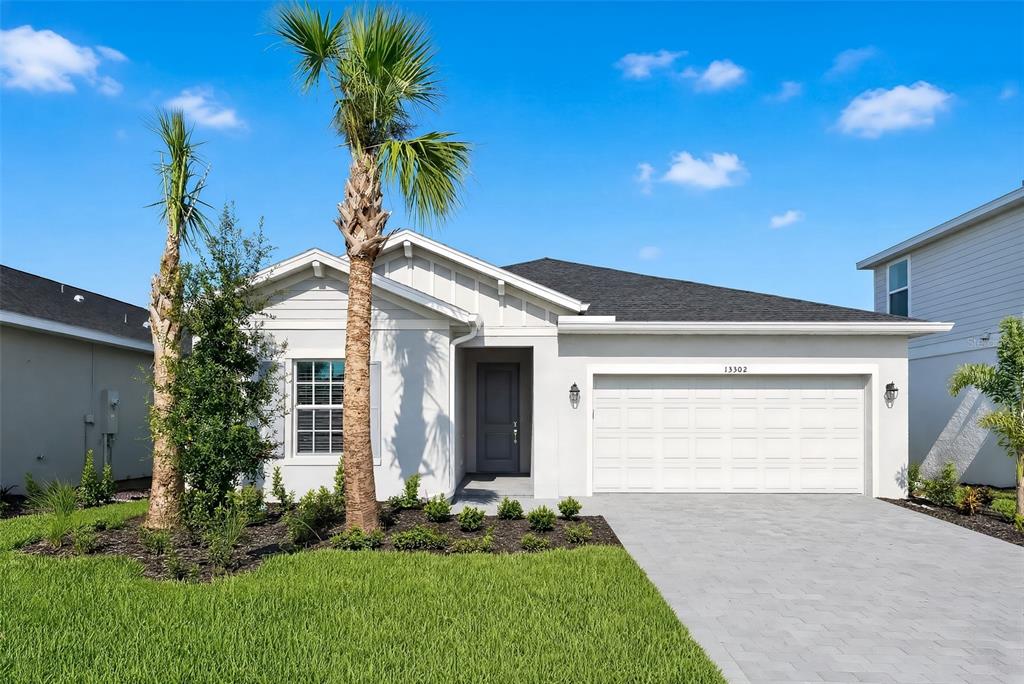 A single-story house with a white exterior, a two-car garage, and a palm tree out front — 13302 GRASSMERE COURT, PUNTA GORDA, FL