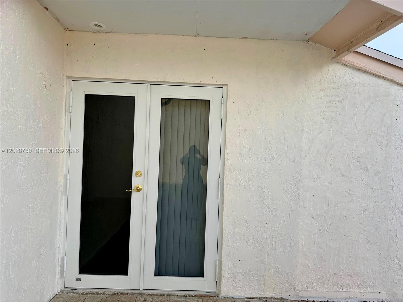 A white double door with glass panels is set into a textured white exterior wall — 19763 SW 124th Ave # 1, Miami FL 33177, MIAMI, FL