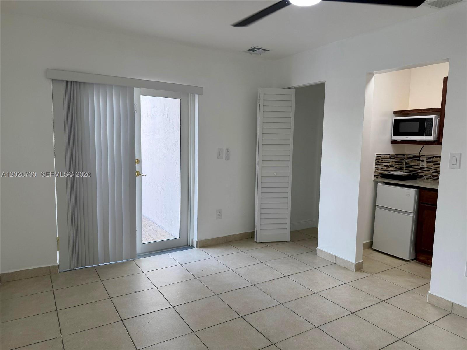 A room with tile flooring, a sliding glass door, a closet, and a kitchenette area — 19763 SW 124th Ave # 1, Miami FL 33177, MIAMI, FL