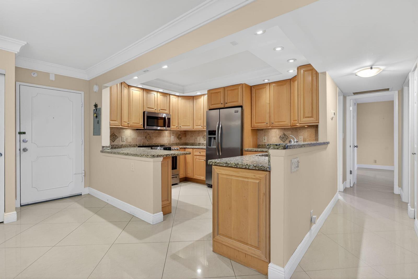 A kitchen with light wood cabinets, granite countertops, and stainless steel appliances — 405 N Ocean Boulevard # 208, Pompano Beach FL 33062, POMPANO BEACH, FL