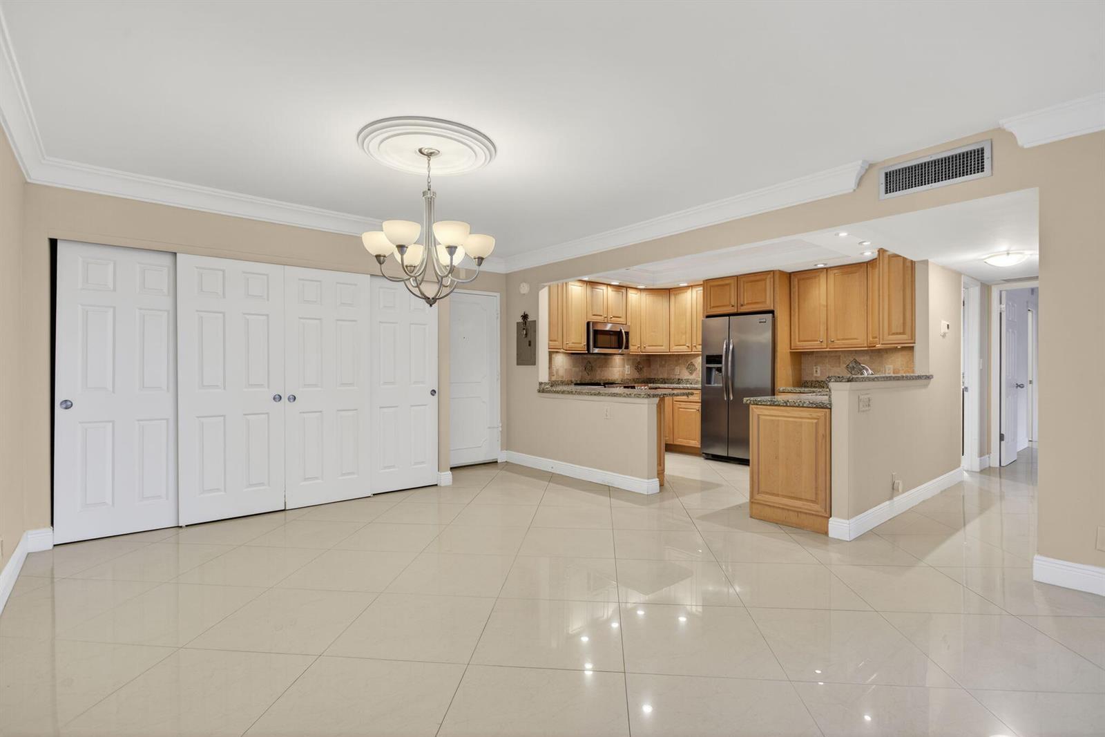 A dining area with tile floors and a chandelier opens to a kitchen with cabinets — 405 N Ocean Boulevard # 208, Pompano Beach FL 33062, POMPANO BEACH, FL