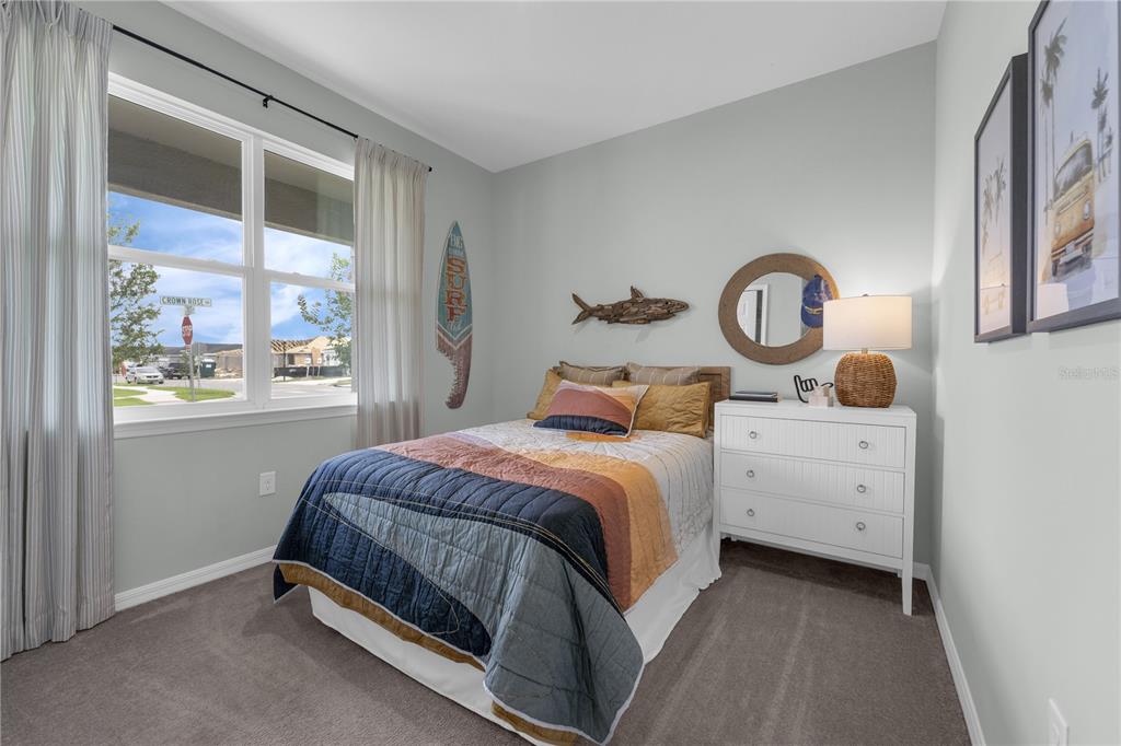 A bedroom features a bed with a surf-themed quilt, a white dresser, and a window — 713 CROWN ROSE DRIVE, EAGLE LAKE, FL