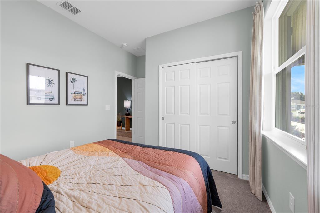 A bedroom features a bed with a colorful quilt, a closet, and framed wall art — 713 CROWN ROSE DRIVE, EAGLE LAKE, FL