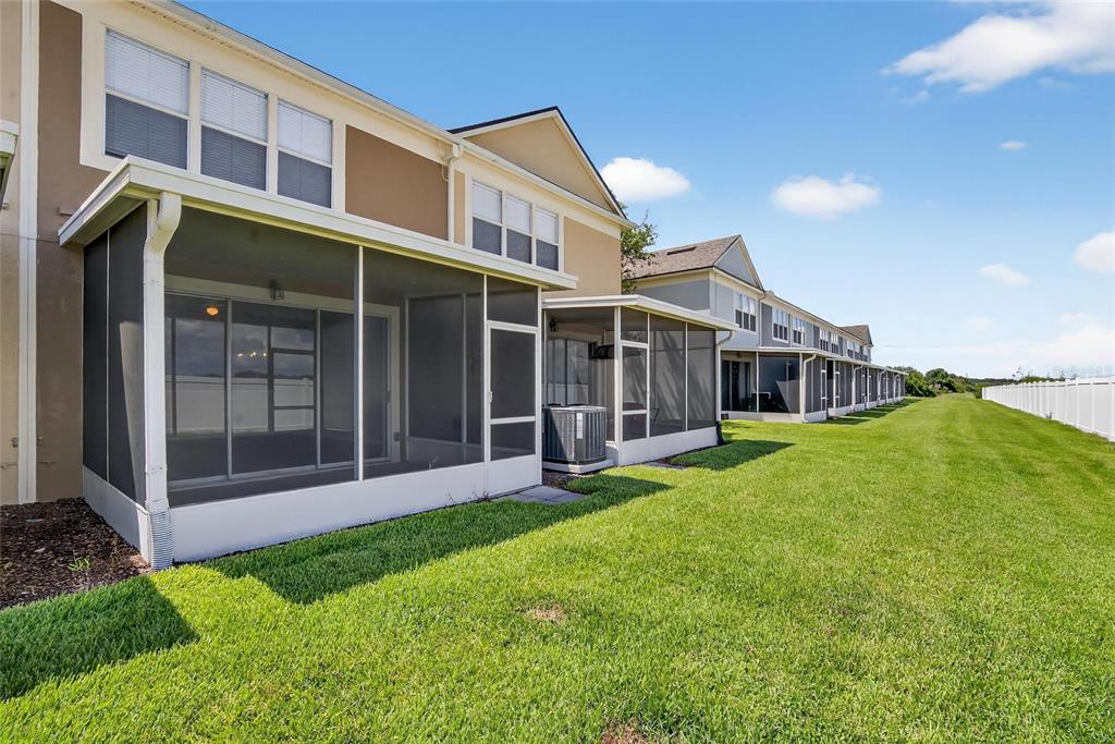 The exterior of a multi-unit townhouse complex features screened-in back patios and a grassy lawn — 4746 POND RIDGE DRIVE, RIVERVIEW, FL