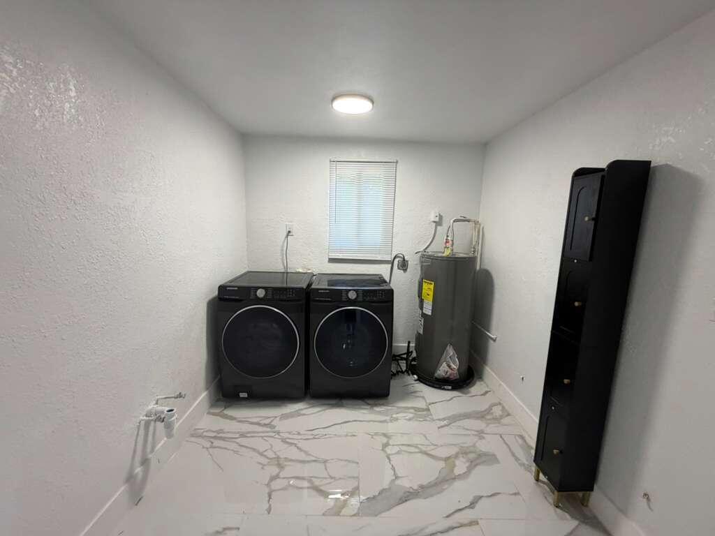 A laundry room with dark appliances, a water heater, and white marble-patterned tile flooring — 160 SE 15th Avenue Unit A, Pompano Beach FL 33060, POMPANO BEACH, FL