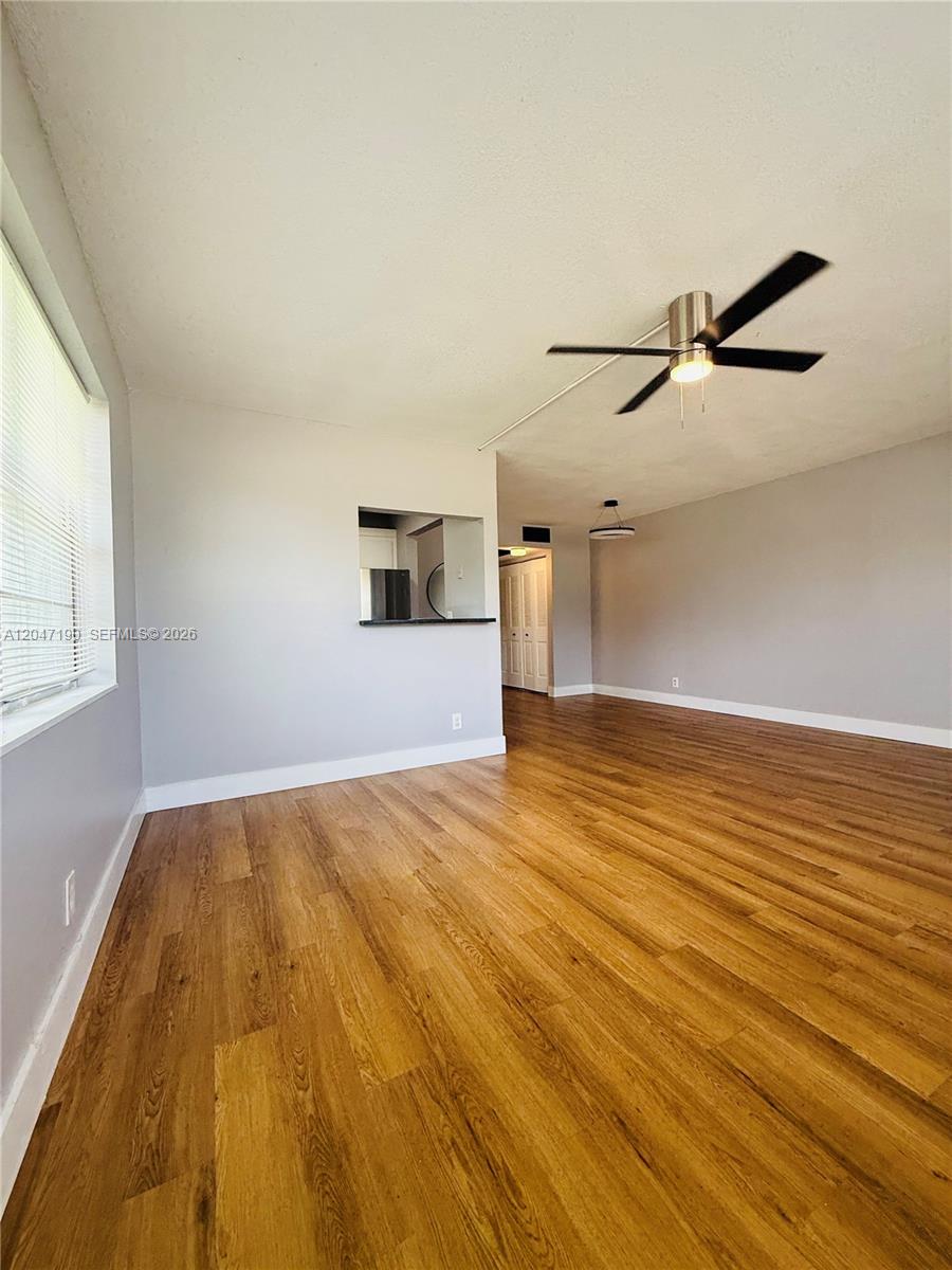 An empty living room features light gray walls, wood-look flooring, and a ceiling fan — 21 Windsor B # b, West Palm Beach FL 33417, WEST PALM BEACH, FL