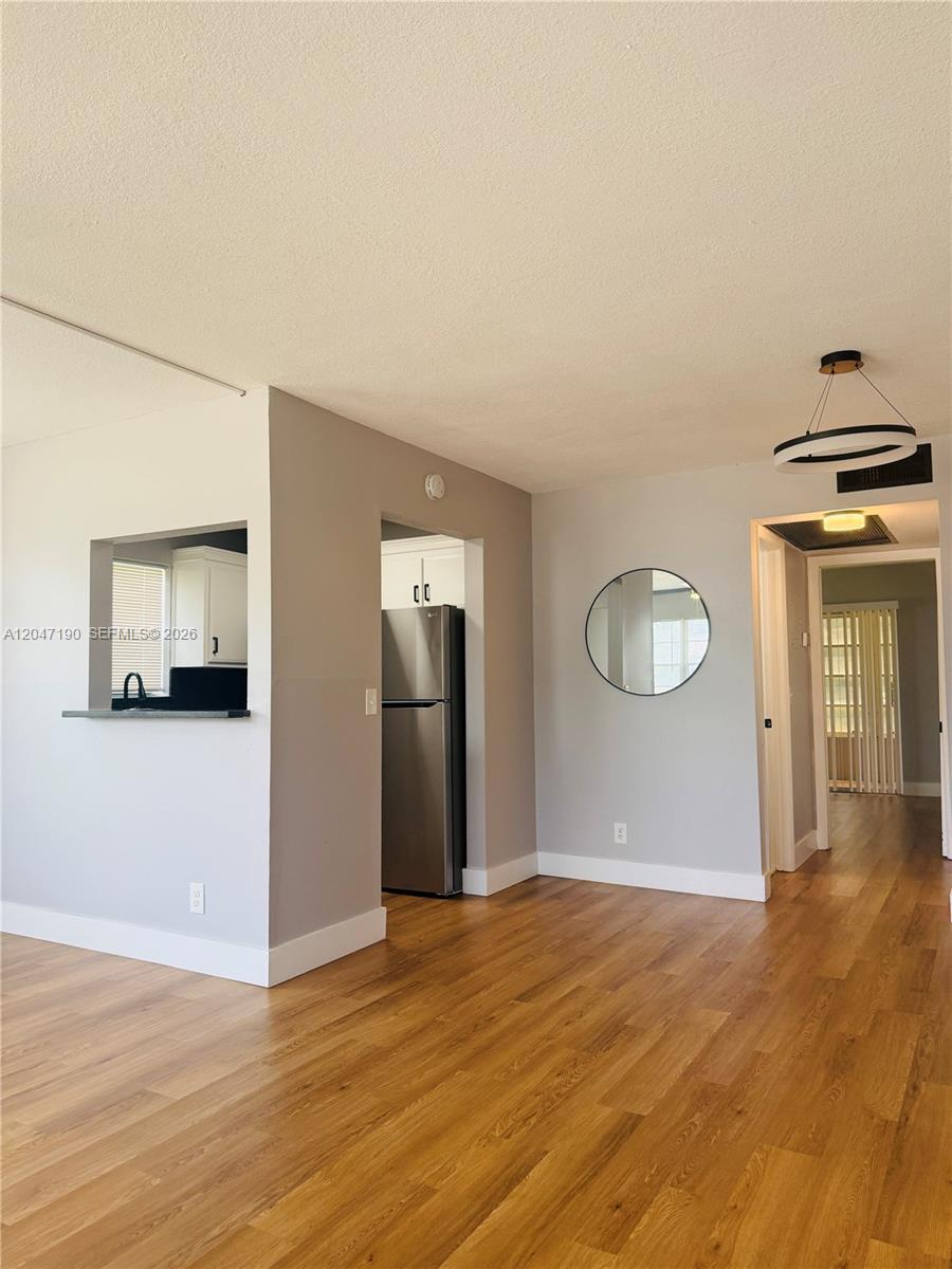 A living area with wood-look flooring leads to a kitchen with stainless steel appliances — 21 Windsor B # b, West Palm Beach FL 33417, WEST PALM BEACH, FL