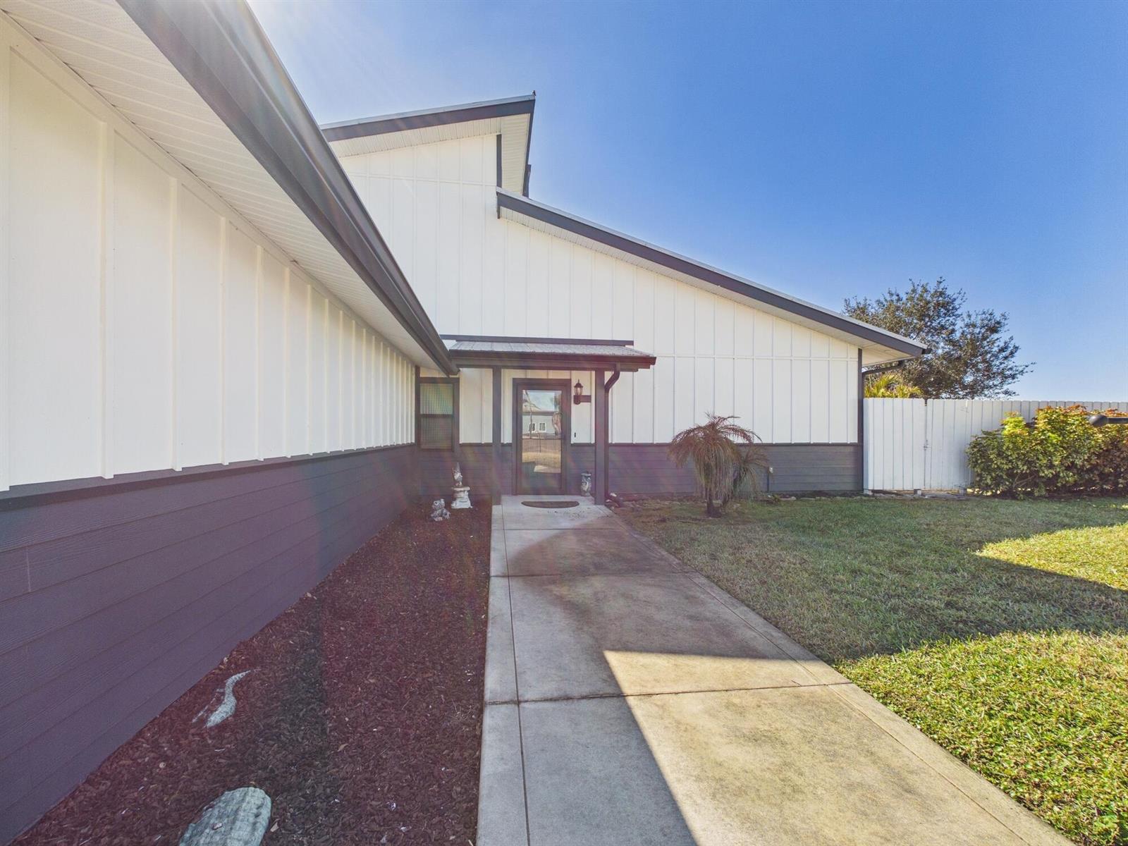 A concrete walkway leads to the front entrance of a house with white vertical siding — 14216 SW 144th Parkway, Okeechobee FL 34974, OKEECHOBEE, FL