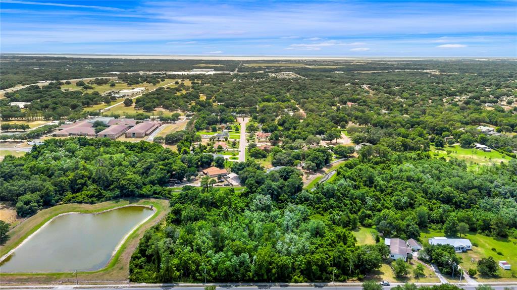 An aerial view shows a rural landscape with a pond, scattered houses, and dense trees — XXXX N HIAWASSEE ROAD, APOPKA, FL