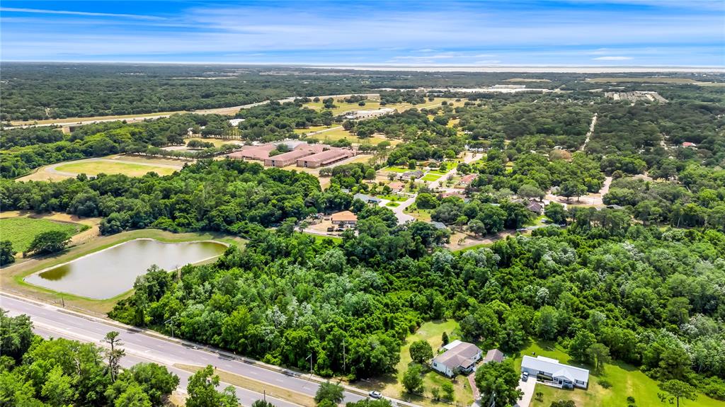 An aerial view shows a pond, dense forest, and scattered buildings in a rural landscape — XXXX N HIAWASSEE ROAD, APOPKA, FL