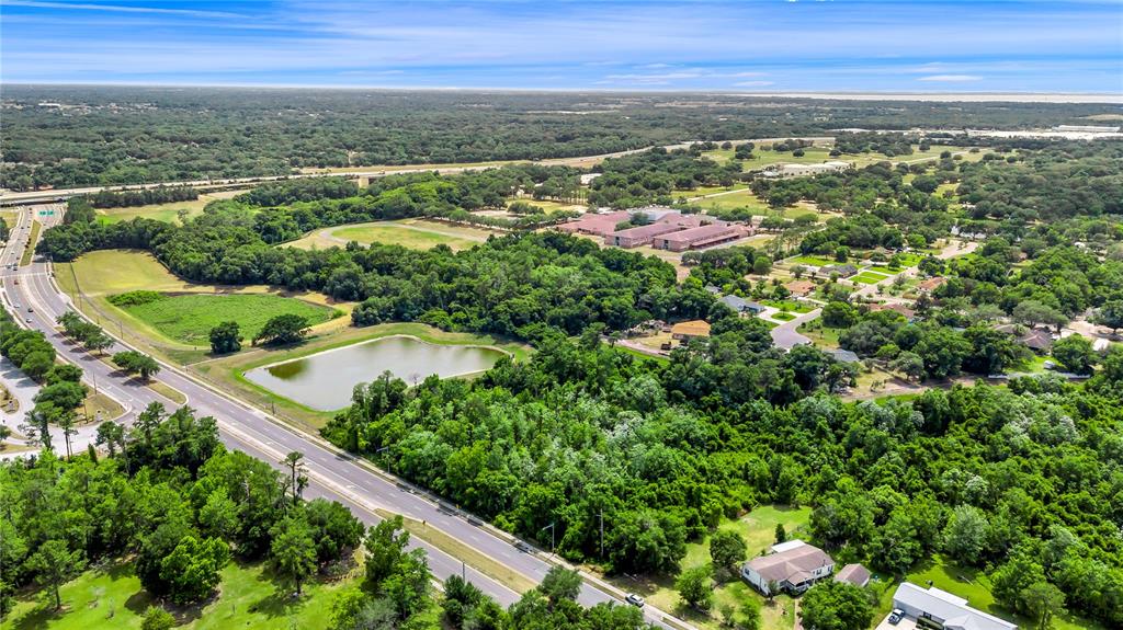 An aerial view shows a road, a pond, dense trees, and several buildings — XXXX N HIAWASSEE ROAD, APOPKA, FL