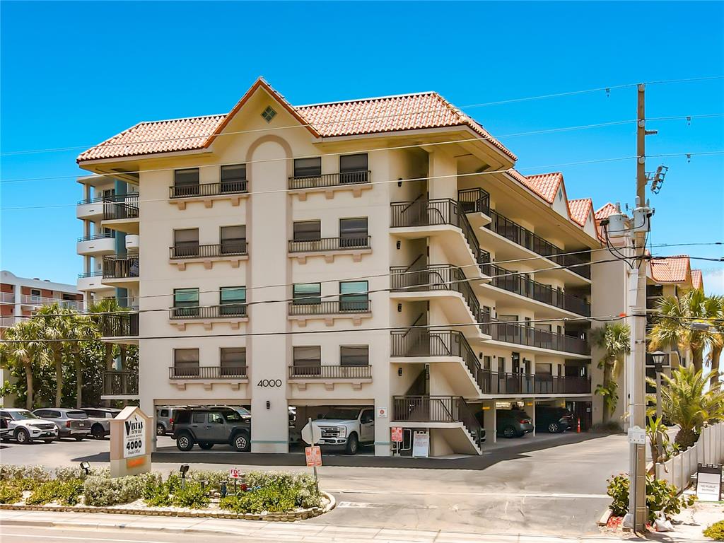 A multi-story apartment building features a covered ground-level parking area and exterior staircases — 4000 GULF BOULEVARD UNIT 203, ST PETE BEACH, FL