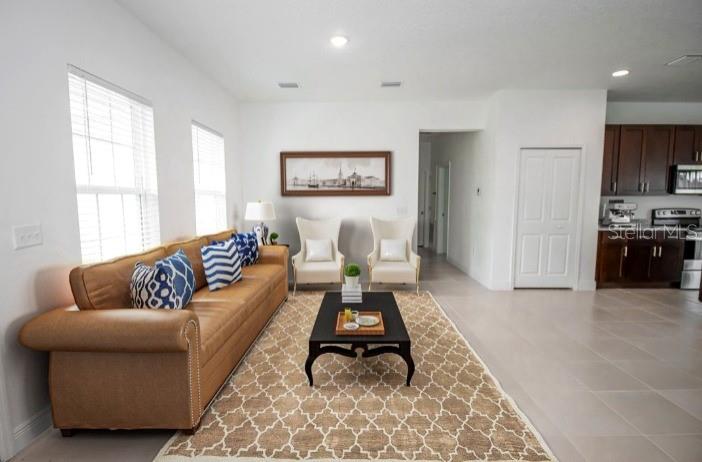A bright, open-concept living area features white tile flooring, a kitchen island, and ceiling fan — 6346 N DARLINGTON DRIVE, DUNNELLON, FL