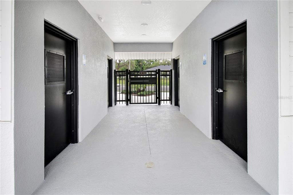 A covered walkway leads to a gated exit between two black doors with metal grilles — 1519 HERITAGE PLACE, OVIEDO, FL
