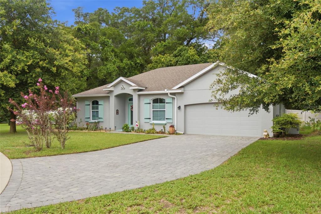 A single-story gray house with light blue shutters and a paved driveway sits among trees — 500 BIRD SONG COURT, DELAND, FL