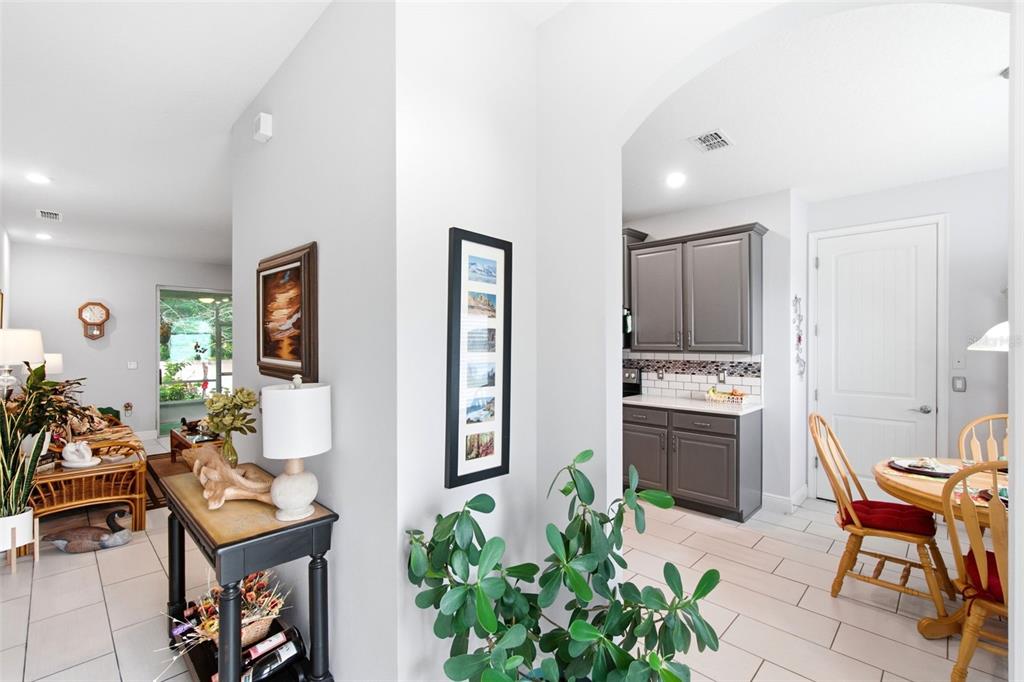 A view from a hallway looking into a living room and a kitchen with gray cabinets — 500 BIRD SONG COURT, DELAND, FL