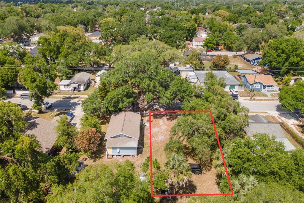 An aerial view shows a vacant, tree-covered residential lot outlined in red next to a house — 1013 E 24TH AVENUE, TAMPA, FL
