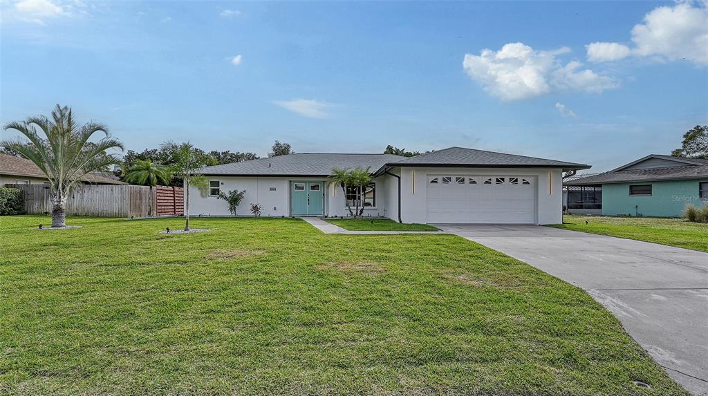 A single-story house with a white exterior, a two-car garage, and a light blue front door — 3924 HELENE STREET, SARASOTA, FL