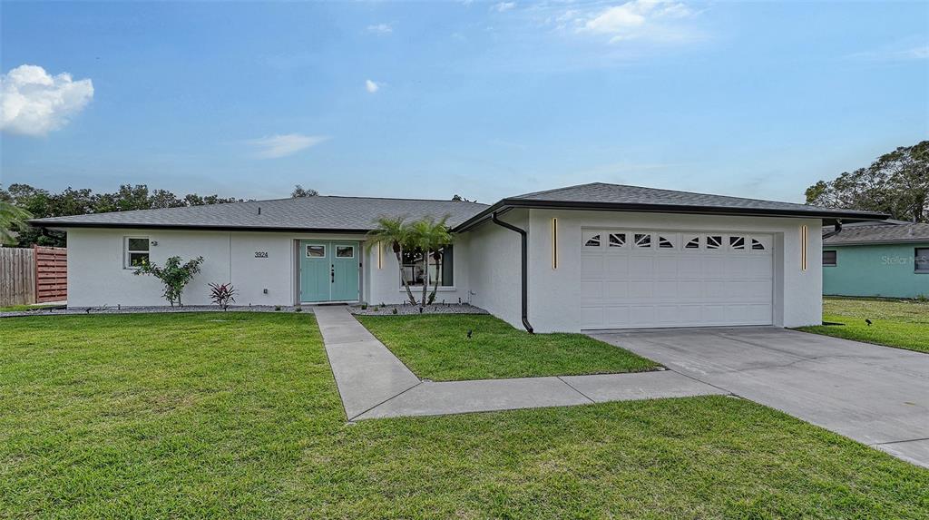 A single-story white house with a two-car garage and a light blue double front door — 3924 HELENE STREET, SARASOTA, FL