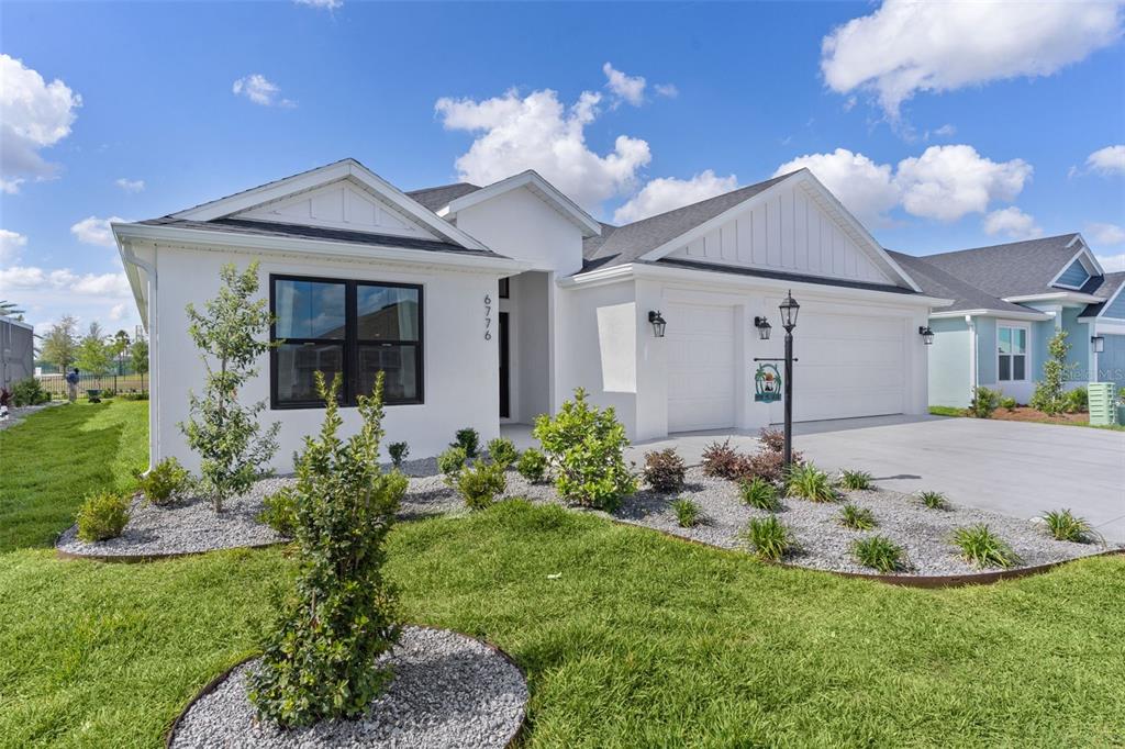A white single-story house with a two-car garage and a landscaped front yard — 6776 ROBINETTE RUN RUN UNIT Robinette Run, THE VILLAGES, FL