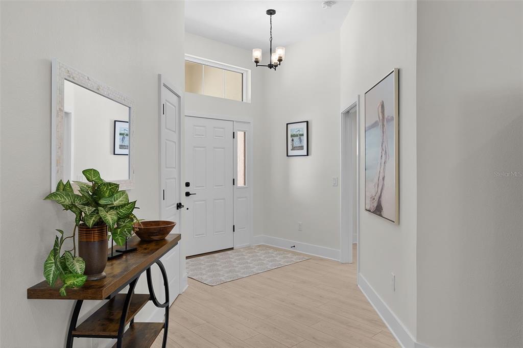 A bright entryway features light wood flooring, a white front door, and a chandelier — 6776 ROBINETTE RUN RUN UNIT Robinette Run, THE VILLAGES, FL