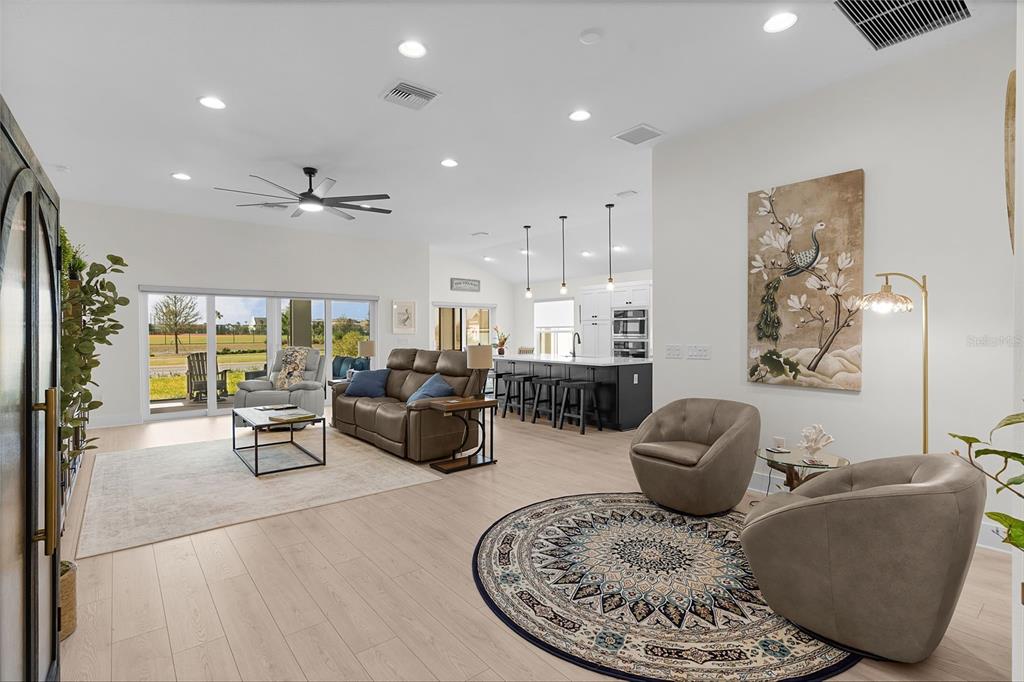 An open-concept living room features light wood floors, a kitchen island, and sliding glass doors — 6776 ROBINETTE RUN RUN UNIT Robinette Run, THE VILLAGES, FL