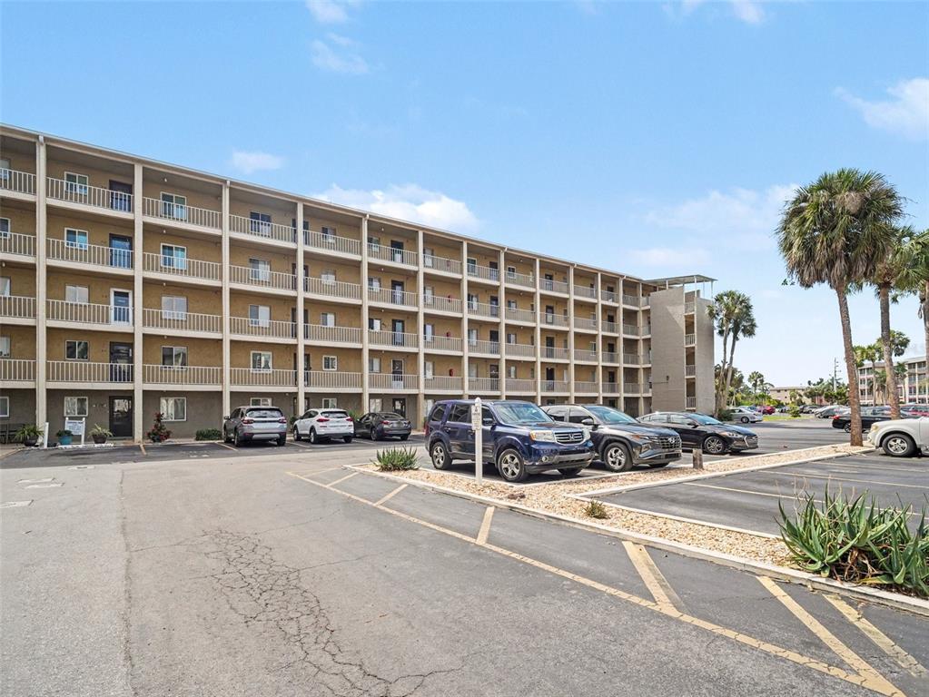 A multi-story apartment building with exterior balconies stands beside a paved parking lot — 3801 LAKE BAYSHORE DRIVE UNIT H413, BRADENTON, FL