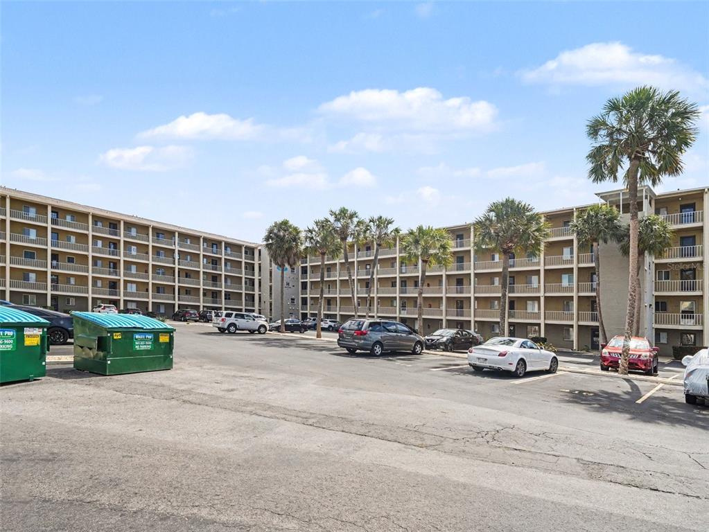 A multi-story apartment building exterior features balconies, a parking lot, and several palm trees — 3801 LAKE BAYSHORE DRIVE UNIT H413, BRADENTON, FL