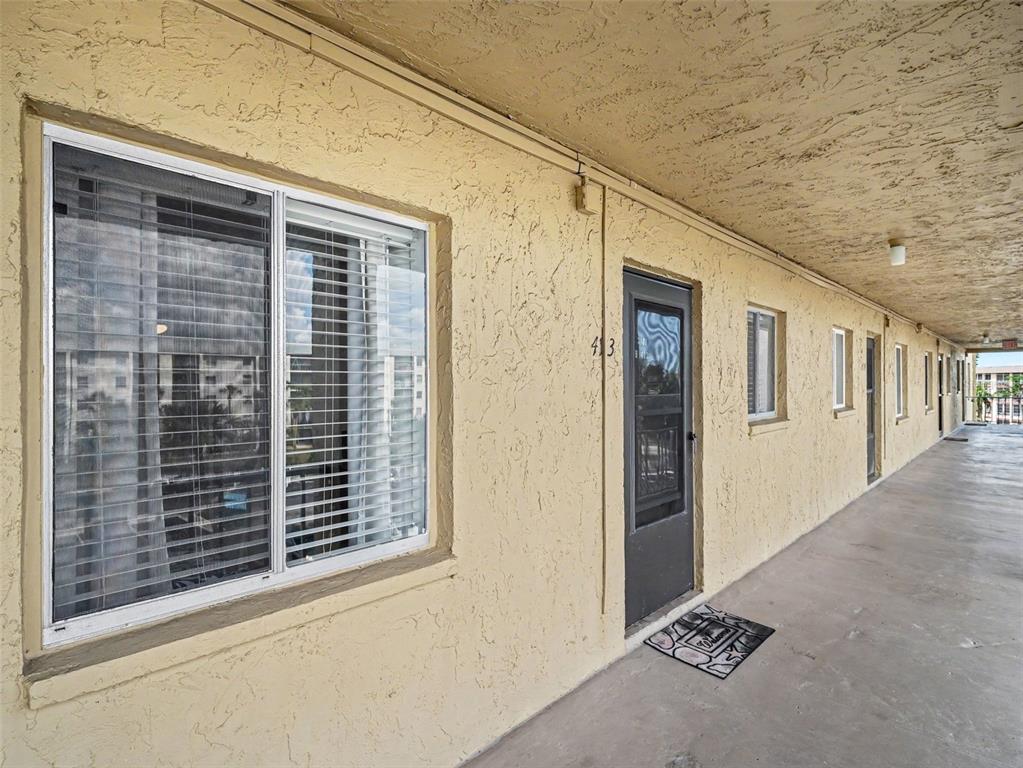 An exterior view of a building corridor featuring a door numbered 413 and windows — 3801 LAKE BAYSHORE DRIVE UNIT H413, BRADENTON, FL