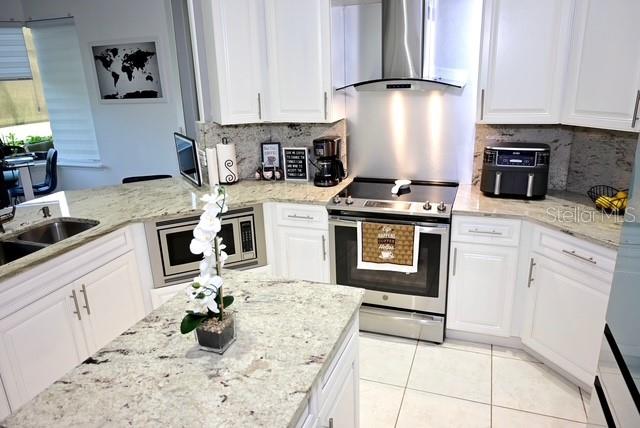 A white kitchen features granite countertops, stainless steel appliances, and a central island — 2270 TOURNAMENT COURT, KISSIMMEE, FL
