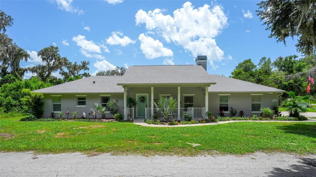 A single-story gray house with a covered front porch sits behind a grassy lawn — 12854 NE 118TH TERRACE, OCKLAWAHA, FL