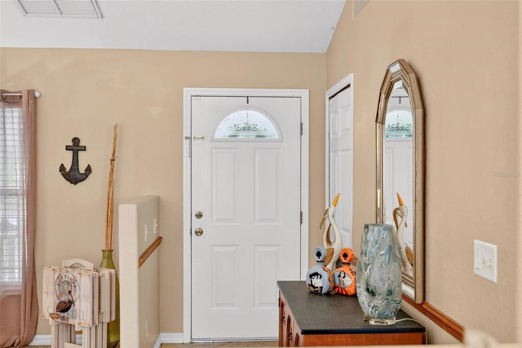 An entryway features a white front door, a wall-mounted anchor, and a mirror above furniture — 12854 NE 118TH TERRACE, OCKLAWAHA, FL