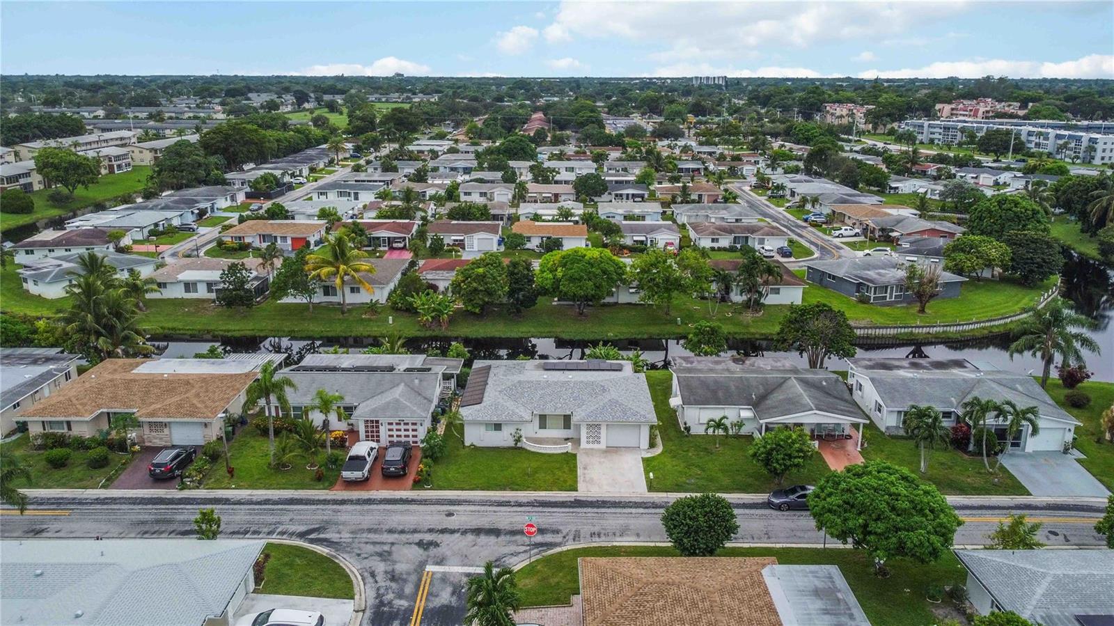 An aerial view shows a suburban neighborhood with single-story houses, a canal, and paved streets — 735 NW 73rd Terrace, Margate FL 33063, MARGATE, FL